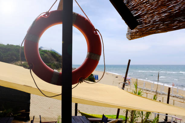 Beautiful beach with sea on blurred background with   lifebuoy and straw roof on foreground. Beautiful beach with sea on blurred background with   lifebuoy and straw roof on foreground. sabaudia stock pictures, royalty-free photos & images