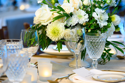 Place setting at a high-end banquet. Plates, flowers, glasses and candles.