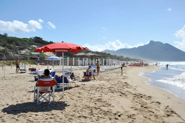 Relaxed people on the Sabaudia beach. Relaxed people on the Sabaudia beach for the summer holidays. The lifeguard keeps watch and the Circeo Mountain is on the background. Sabaudia, Lazio, Italy. sabaudia stock pictures, royalty-free photos & images