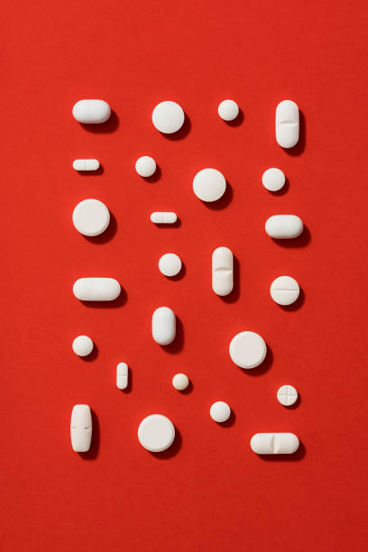 White pills on red background stock photo