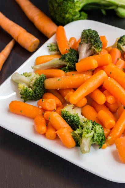 istock Vegetable salad: broccoli and carrots in a white plate on a black background 1161241714