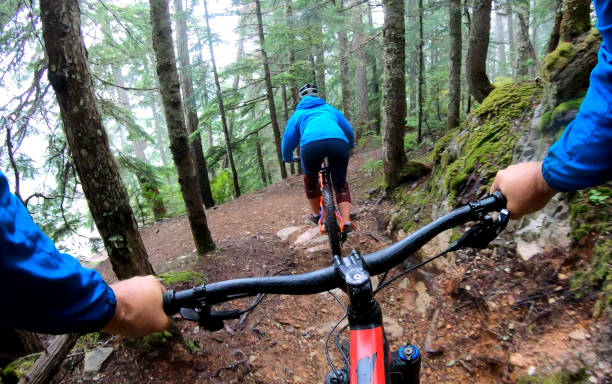 istock View past handlebars to young woman mountain biker riding on rainforest trail 1161241765