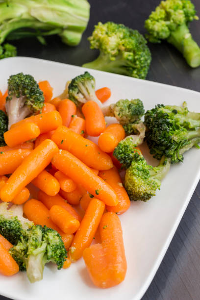 istock Vegetable salad: broccoli and carrots in a white plate on a black background 1161241803
