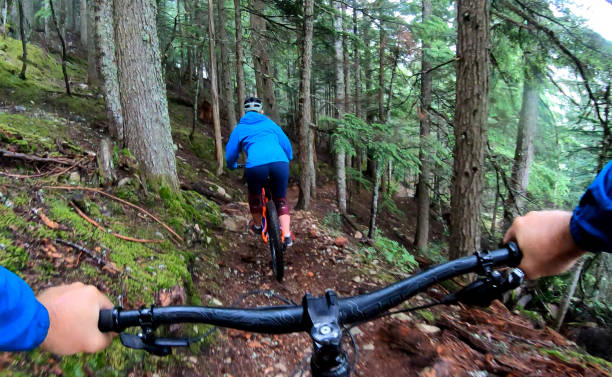 istock View past handlebars to young woman mountain biker riding on rainforest trail 1161241870