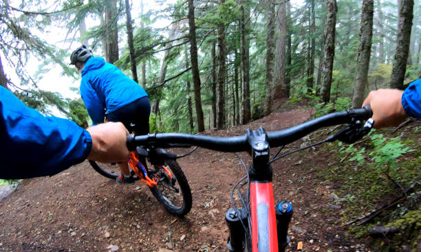 istock View past handlebars to young woman mountain biker riding on rainforest trail 1161241943