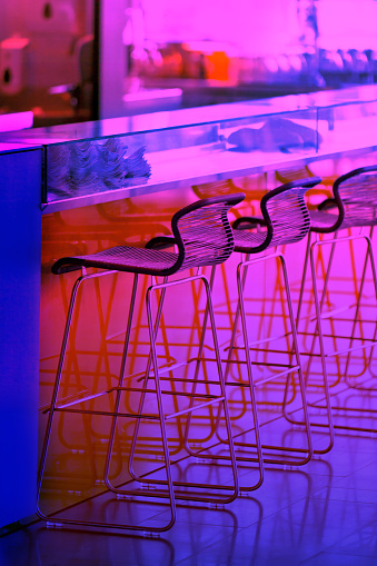 Neon colored Empty row of stools at a close bar. Vertical shot
