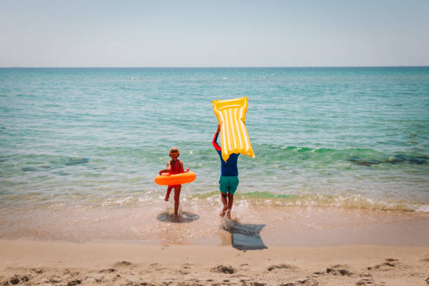 istock happy boy and girl with floaties run swim on beach 1161248130