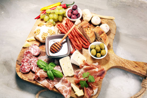 istock Cutting board with prosciutto, salami, cheese,bread and olives on dark stone background 1161251610
