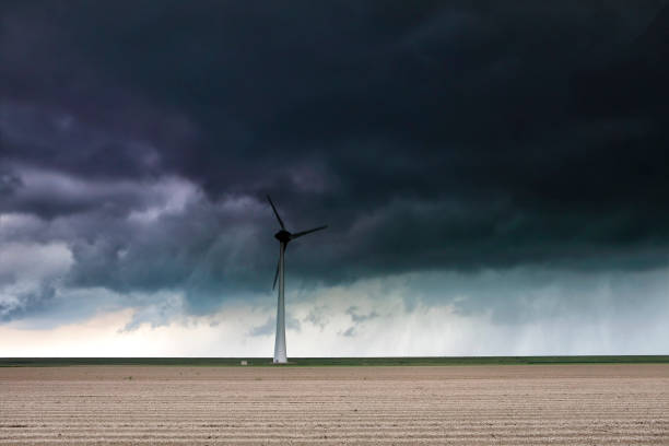 istock dark stormy sky over plowed field and wind turbine 1161251999