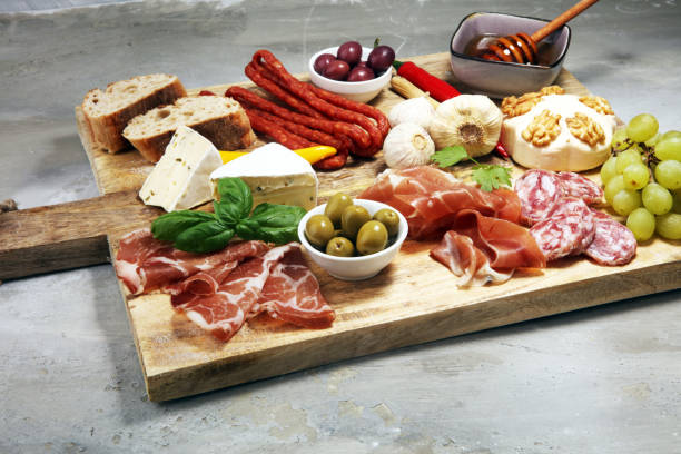 istock Cutting board with prosciutto, salami, cheese,bread and olives on dark stone background 1161252056