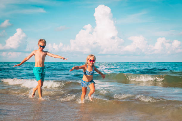 istock happy boy and girl run play at beach 1161252184
