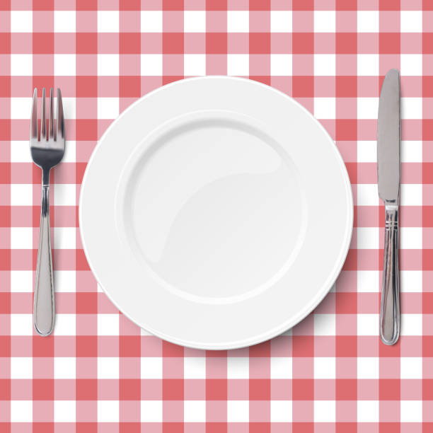 istock Close up view of empty white dish with knife and fork placed on classic checkered red tablecloth seamless background. View from above. 1161253598