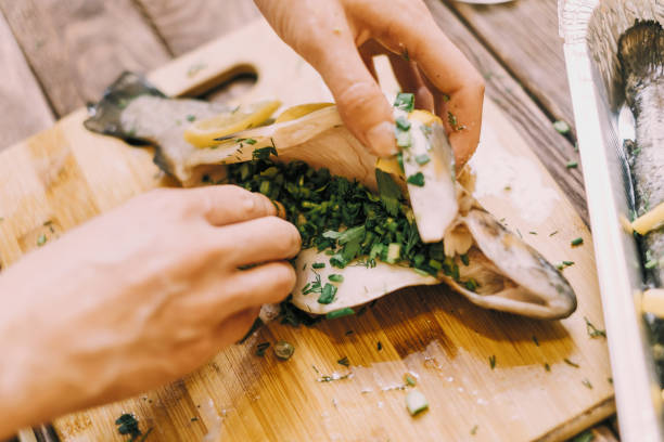 istock Woman putting greenery in raw fish for cooking. 1161253945