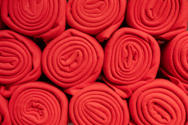 Rolls of many red plaids stand on the shelf