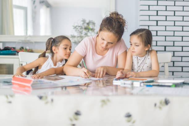 mother helping daughters with homework - homework pencil people indoors imagens e fotografias de stock