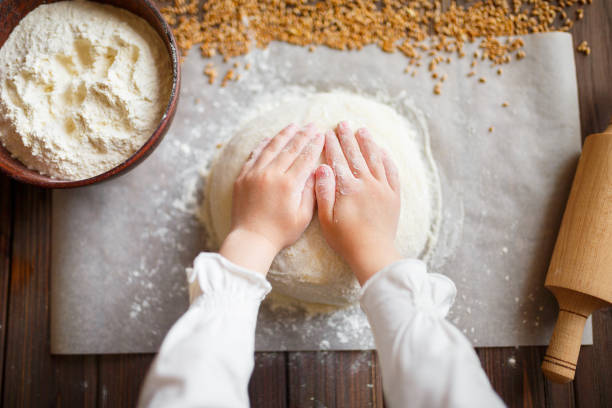 Detail of hands kneading dough on wooden table