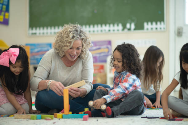 istock Caucasian female teacher playing blocks with her students 1161275038
