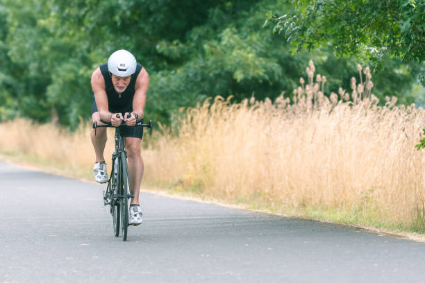 istock Senior triathlete cycling on a paved trail 1161275912