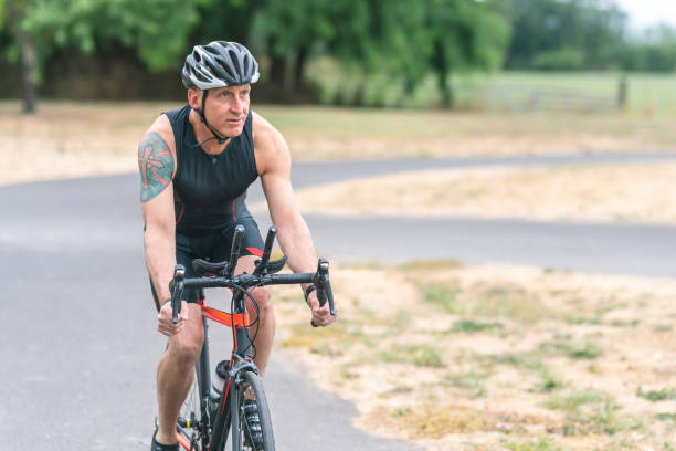istock Senior triathlete cycling on a paved trail 1161275925