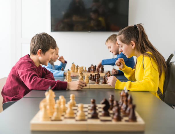 Kids of different ages, boys and girls, playing chess on the tournament in the chess club Kids of different ages, boys and girls, playing chess on the tournament in the chess club chess timer stock pictures, royalty-free photos & images