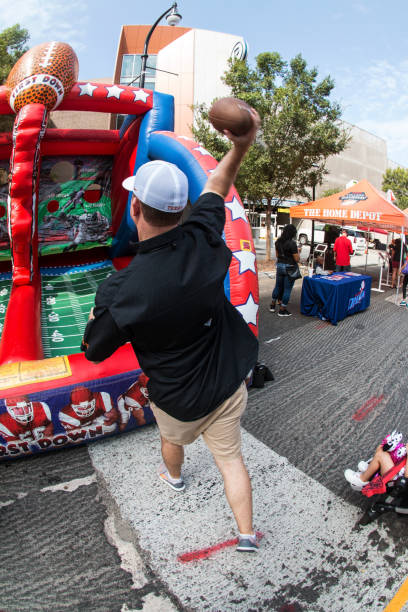 Man Throws Football Toward Targets At College Football Fan Fest Atlanta, GA, USA - August 25, 2018:  A man throws footballs at targets in an inflatable game at the Chick-Fil-A Football Fan Fest to commemorate the start of the college football season on August 25, 2018 in Atlanta, GA. georgia football stock pictures, royalty-free photos & images