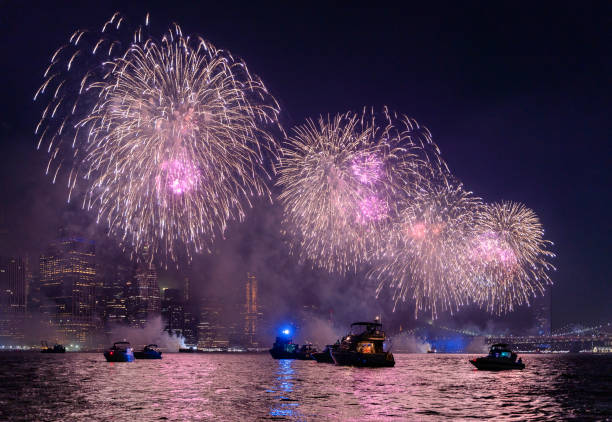 crowd watching the colorful holiday's july, 4th independenсу day fireworks at east river, in front of manhattan downtown, from many yachts and boats. - large group of people flash imagens e fotografias de stock