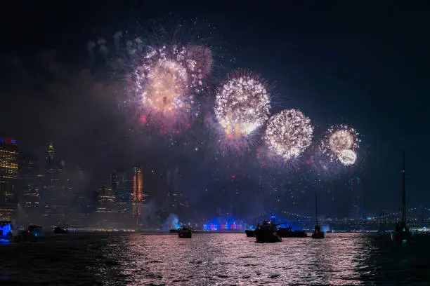 Photo of Crowd watching the colorful holiday's July, 4th Independenсу Day fireworks at East River, in front of Manhattan Downtown, from many yachts and boats.