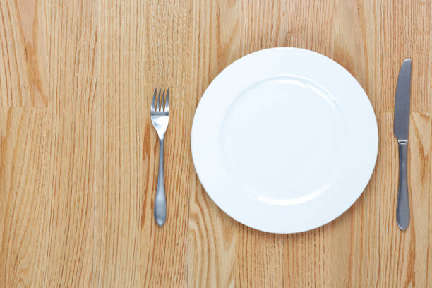 istock A dining fork and knife beside a plate on a wood table with copy space 1161286270