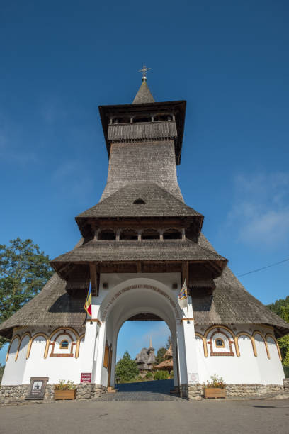 Barsana, Romania - Sep 26, 2018:  Looking through unique entrance with very high, wooden shingle roofed tower to the grounds of Barsana Monastery, Maramures, Romaina