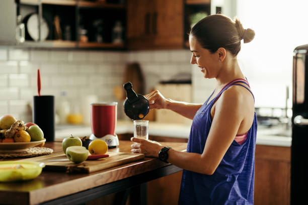 istock Happy sportswoman pouring herself fruit smoothie in the kitchen. 1161289636