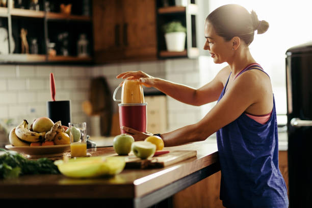 junge sportlerin macht gesunden smoothie in der küche. - routine foods and drinks clothing household equipment stock-fotos und bilder