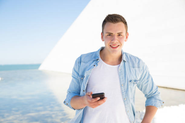 istock Portrait of cheerful young man using cellphone on vacations 1161300311