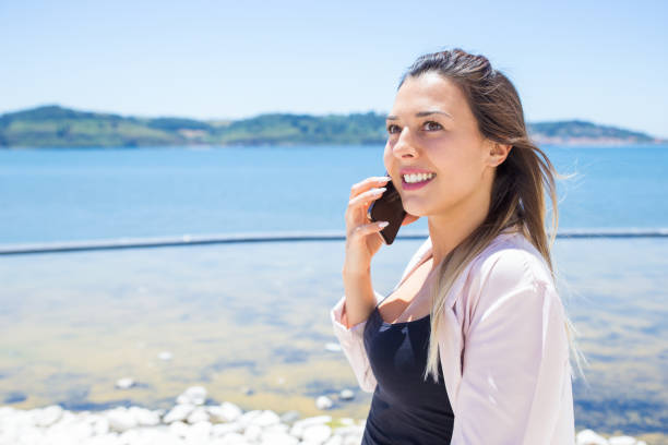 istock Pensive happy lady with mobile phone standing by river 1161307384