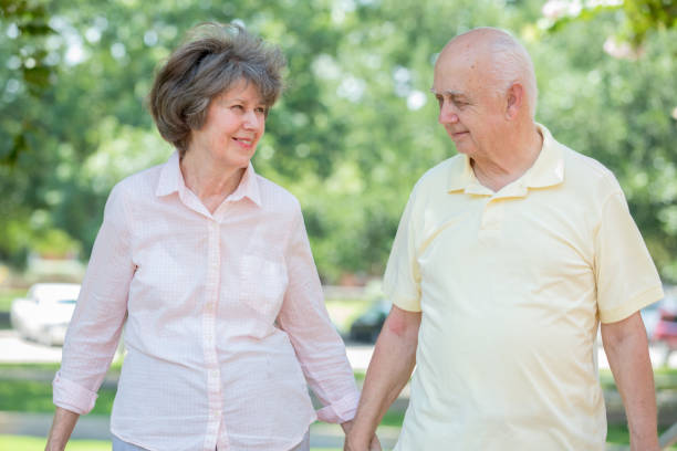 istock Senior couple walk through public park while holding hands 1161308111