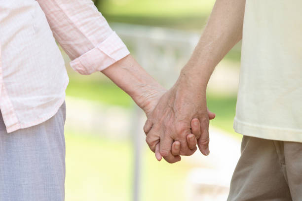 istock Senior man holds hands with wife while walking in park 1161308232