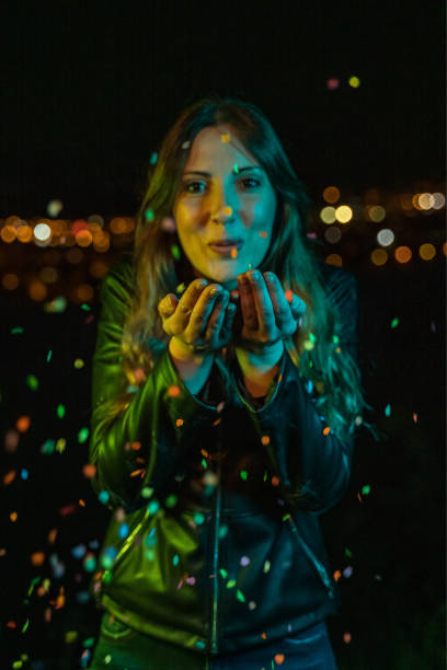 istock Young woman blowing confetti at night party 1161308735