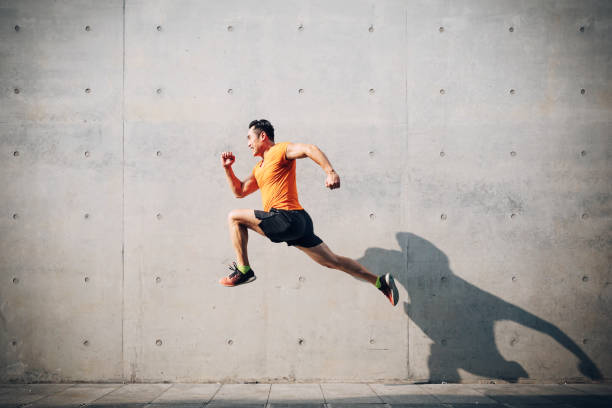 sportlicher asiatischer mittelsmann läuft und springt gegen denkladen. gesundheits- und fitnesskonzept. - hochspringen stock-fotos und bilder