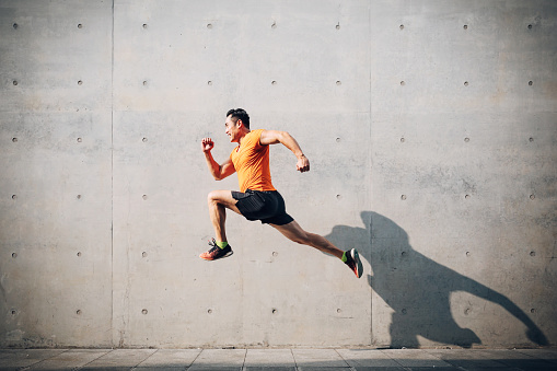 Deportista asiático Medio hombre corriendo y saltando contra el obturador. Concepto de salud y fitness. photo