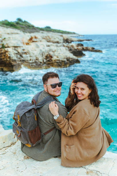 istock couple sitting on the cliff looking at sea 1161315298