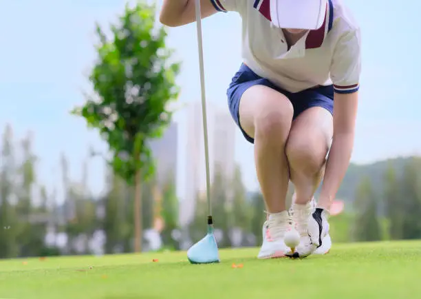 woman golf player holding golf ball laying on wooden tee on T-OFF, prepare and ready to hit the ball to the destination targe in the fairway