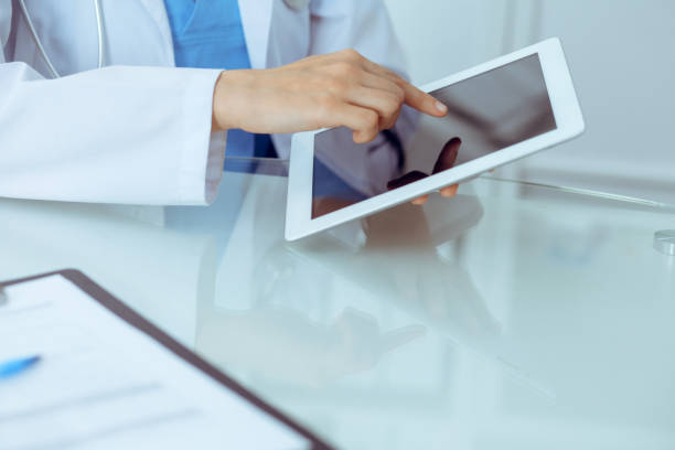 istock Female doctor using tablet computer while sitting at the workplace, close-up of hands. Medicine, healthcare and help concept 1161321511
