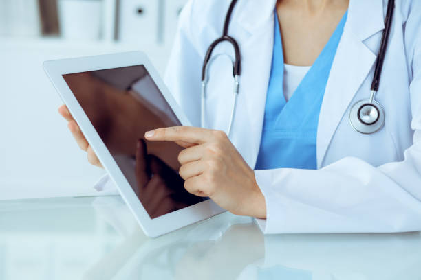 istock Female doctor using tablet computer while sitting at the workplace, close-up of hands. Medicine, healthcare and help concept 1161321514