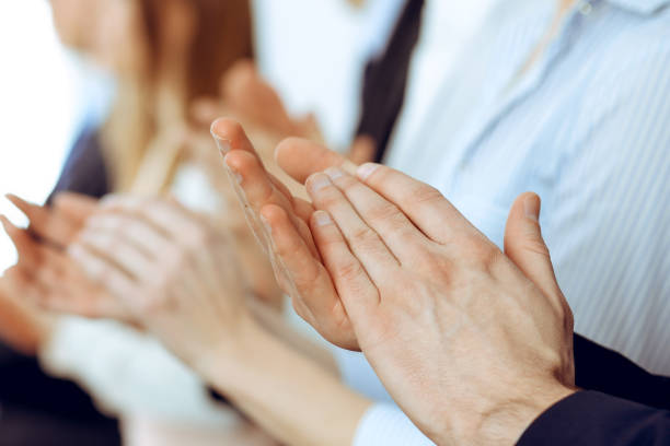 Business people clapping and applause at meeting or conference, close-up of hands. Group of unknown businessmen and women in modern white office. Success teamwork or corporate coaching concept. gente de negocios aplaudiendo y aplaudiendo en la reunión o conferencia, primer plano de las manos. grupo de hombres de negocios y mujeres desconocidos en la oficina blanca moderna. trabajo en equipo de éxito o concepto de coaching corporativo
