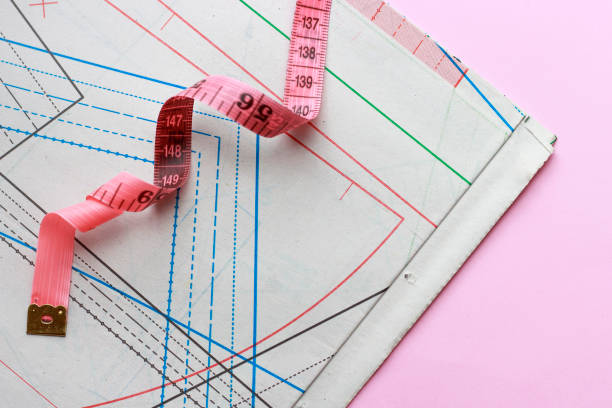 istock Measuring tape and paper pattern for sewing on a pink background, closeup 1161329028