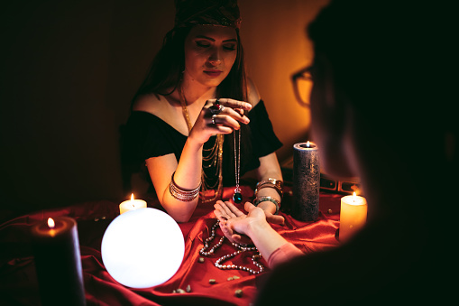 Young female fortune teller reading from palm.