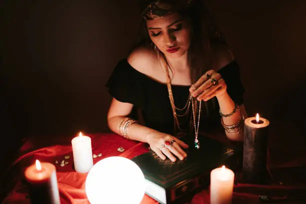 Young female fortune teller and book of spells.