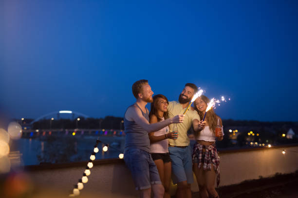 istock Friends enjoying a rooftop party and dancing with sparklers 1161333024