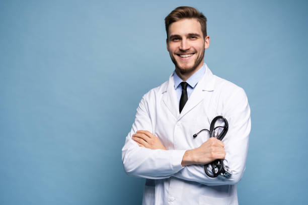 portret pewnego siebie młodego lekarza na niebieskim tle. - cheerful happiness surgeon success zdjęcia i obrazy z banku zdjęć