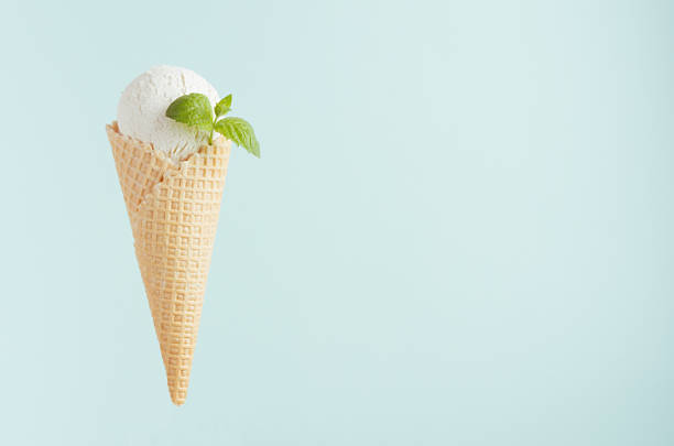 istock White creamy ice cream in crisp waffle cone with green mint leaf on soft light pastel green background, copy space. 1161336402