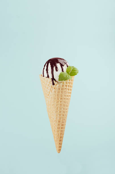 istock Classic white ice cream in crisp waffle cone with chocolate sauce, fresh mint leaf on green background, vertical. 1161336404